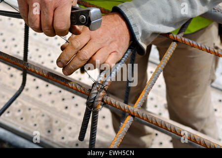 Lavoratore utilizzando il filo e pinze per il tirante di rinforzo in acciaio insieme di barre per cemento armato pour Foto Stock