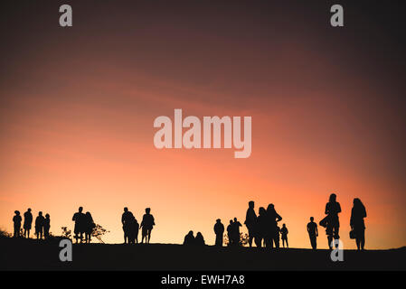 Silhouette di persone a guardare la luna salire in Broome (scala per la Luna), dopo il tramonto Foto Stock