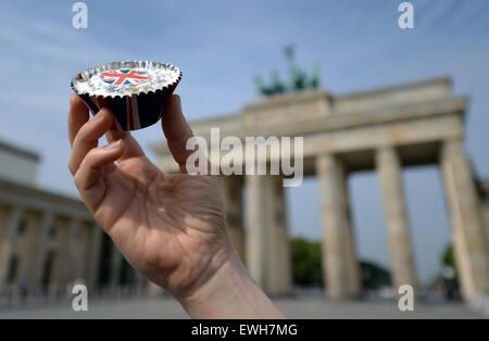 Berlino, Germania. Il 26 giugno, 2015. Una donna presenta un cupcake fatti in casa con una bandiera britannica sulla parte superiore di fronte alla Porta di Brandeburgo a Berlino, Germania, 26 giugno 2015. La Gran Bretagna è la Regina Elisabetta II e suo marito sono sulla loro quinta visita di Stato in Germania dal 23 al 26 giugno. Foto: BRITTA PEDERSEN/dpa Credito: dpa picture alliance/Alamy Live News Foto Stock