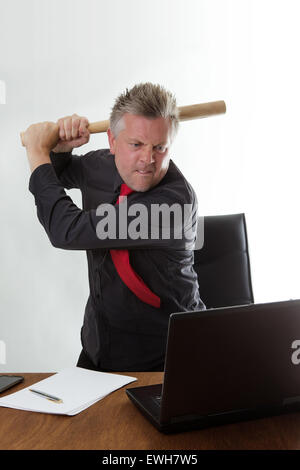 Imprenditore arrivare molto pazzi per colpire il suo computer con una mazza da baseball Foto Stock