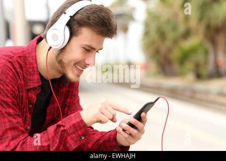 Adolescente di apprendimento dello studente con il corso on-line in uno smart phone in una stazione ferroviaria mentre è in attesa Foto Stock