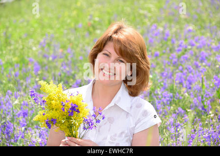 Donna adulta in un prato con fiori selvatici Foto Stock