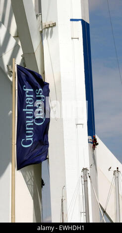 Portsmouth, Hampshire, Regno Unito. Il 26 giugno, 2015. L'inizio di due settimane di lavoro di vernice sulla Spinnaker Tower ha iniziato a disegnare la folla verso il basso. Il dipinto è stato ritardato dopo la vernice è stato catturato in un incidente stradale sul percorso verso la torre. Questo porta un nuovo significato a guardare la vernice asciuga GV mostra workman applicazione di vernice per la Spinnaker Tower Emirates ha accettato di modificare il design di blu, bianco e oro. Credito: Jason Kay/Alamy Live News Foto Stock