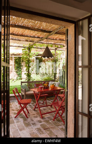 Dipinto di rosso mobili austriaca sulla terrazza ombreggiata con stagno di luce e di ombra panca Balinese Foto Stock