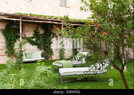 Lettini per prendere il sole in giardino con alberi di arancio Foto Stock