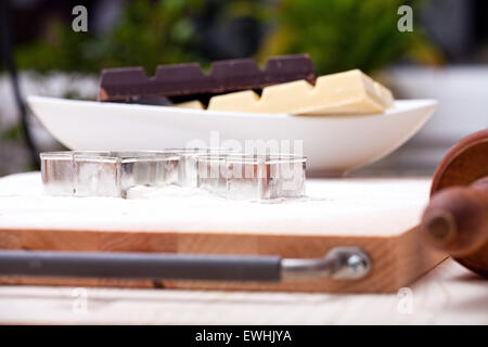 Cookie cutter e bianco e scuro cioccolato di copertura sul forno infarinata board Foto Stock