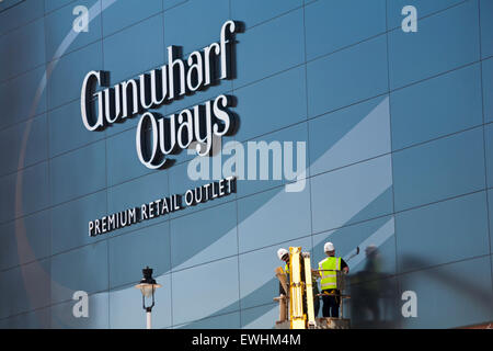 Operai in cherry picker lavorando sulla facciata di Gunwharf Quays Retail Premium Outlet a Portsmouth in giugno Foto Stock