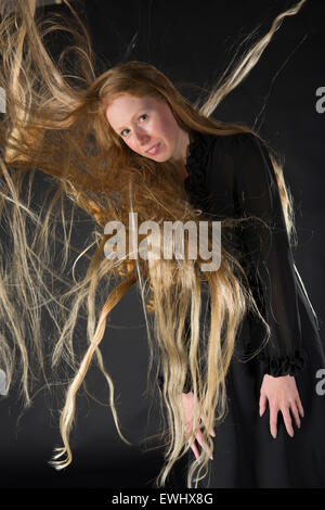 Donna bionda con il vento che soffia attraverso i capelli lunghi Foto Stock