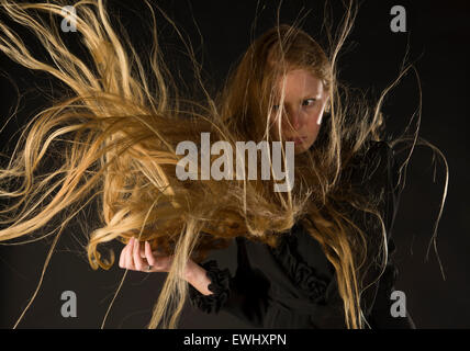 Donna bionda con il vento che soffia attraverso i capelli lunghi Foto Stock