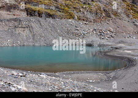 Bollitore foro formazioni di roccia riempita con acqua blu a sinistra dietro dal ghiacciaio Islanda Foto Stock