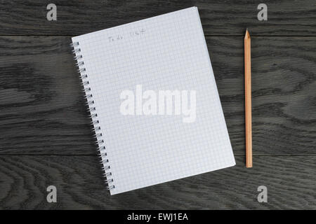 Elenco delle cose da fare di una frase in Blocco note con pagine a scacchi su grigio tavolo in legno e matita Foto Stock