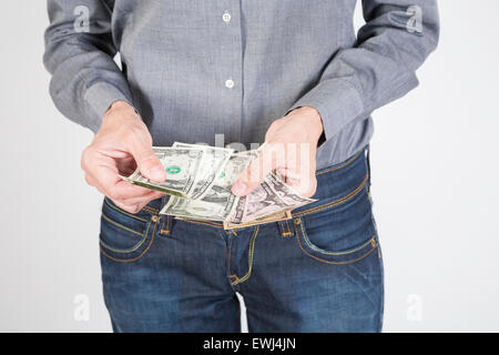 Donna blu jeans pantaloni e camicia grigia la valuta di conteggio denaro contante uno cinque dieci e venti banconote di dollari nelle sue mani isol Foto Stock