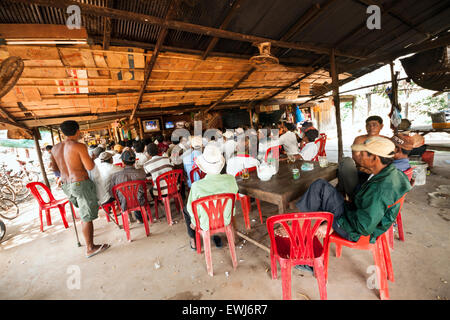 I cambogiani guarda e scommesse sul match di boxe in un villaggio rurale shop. Foto Stock