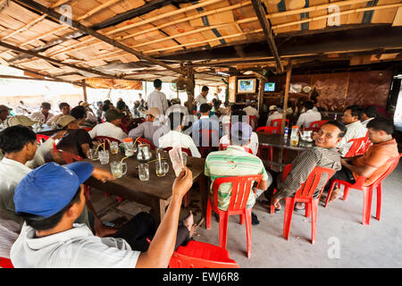 I cambogiani guarda e scommesse sul match di boxe in un villaggio rurale shop. Foto Stock