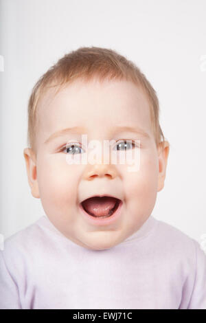 Ritratto di otto mesi di età adorabile bionda simpatico baby pink velvet onesie aprire bocca gridare urlare sorridente faccia felice isolato su w Foto Stock