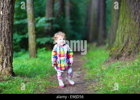 Sweet Baby girl in una giacca impermeabile e stivali a camminare in un parco di autunno Foto Stock