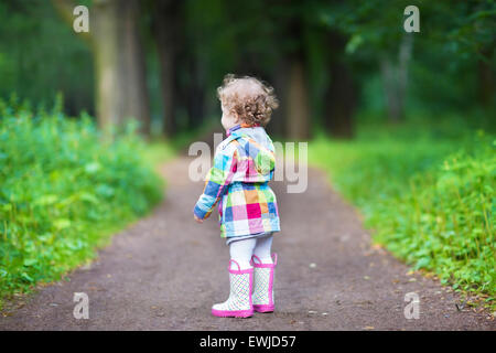 Carino curly bambina in un parco, vista dal suo indietro Foto Stock