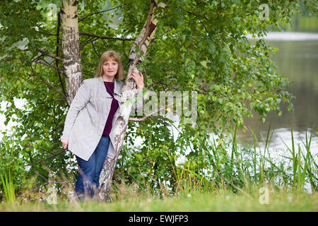 Bella Signora a piedi di un lago in un freddo giorno di autunno Foto Stock