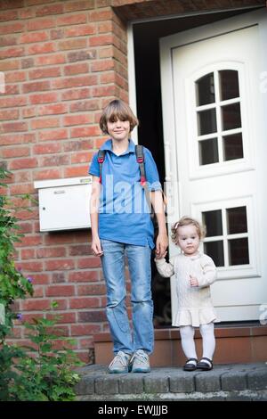 Il fratello e la sorella del bambino di lasciare a casa il loro primo giorno di scuola e asilo Foto Stock