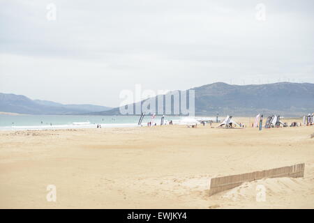 Surfisti sulla spiaggia in una giornata di vento di Tarifa, Spagna, nel novembre 23th, 2009. Impianti di energia eolica sulla cima della montagna. Foto Stock