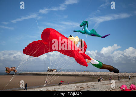 Morecambe, Lancashire, Regno Unito 27 Giugno, 2015. Il molo di pietra catturano il vento il Kite Festival un festival annuale sul lungomare di Morecambe, quando per tutta la giornata i cieli sono pieni delle più spettacolari forme, colori e le creazioni. In primo piano sono state singola linea aquiloni di tutti i tipi e dimensioni, incluso un massiccio 30 metri lungo il polpo gonfiabile, battenti cavalli, cani e anche pesce. Plus 2-line e 4-line stunt kites. Foto Stock