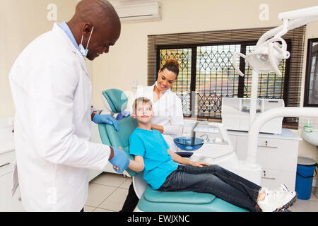 Gentile dentista mi congratulo con piccolo ragazzo per una operazione di successo Foto Stock