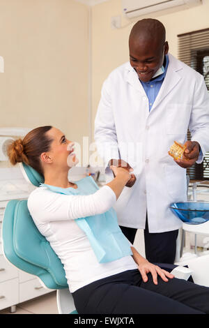 Allegro giovane donna si stringono la mano con il dentista dopo denti checkup Foto Stock