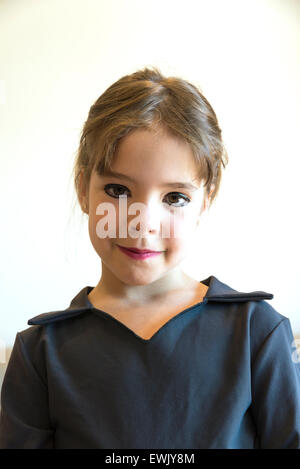 Bambina ritratto di parted per il trucco agli occhi e labbra dipinte e vestite di nero e isolato su sfondo bianco Foto Stock