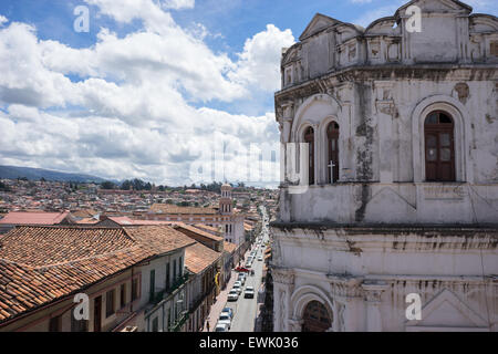 Vista della strada e bianco edificio coloniale di Cuenca in Ecuador con una croce nella finestra di antiquariato. Foto Stock