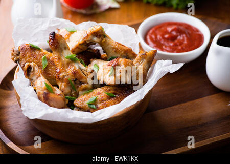 Alette di pollo fritte con salse in ciotola di legno, fuoco selettivo Foto Stock