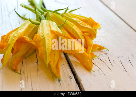 Fiori commestibili di zucchine su un tavolo bianco Foto Stock