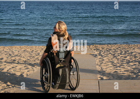 Una donna su una sedia a rotelle su una spiaggia rampa di accesso Foto Stock