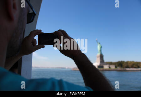 Uomo di prendere una fotografia della statua della libertà sul suo telefono cellulare Foto Stock