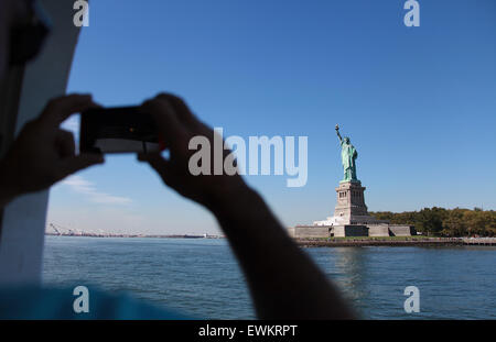 Uomo di prendere una fotografia della statua della libertà sul suo telefono cellulare Foto Stock