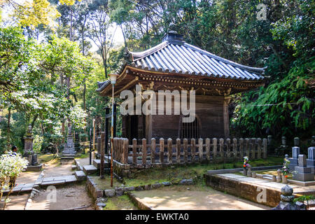 Giappone, Kyoto Arashiyama. Nison-ji tempio buddista. Ornati in legno pavillion impostato su hiolltop con recinto intorno e in primo piano i marcatori di grave. Foto Stock