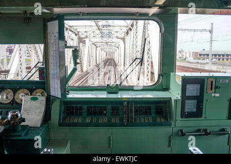 Japanese Railway Commuter Train. Vista anteriore attraverso il driver per una finestra di una cabina come il treno viaggia su una scatola ponte doratore di Osaka in Giappone. Foto Stock