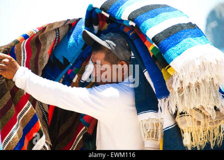 Uomo locale di vendita coperte fatte a mano sulla spiaggia per i clienti. Foto Stock