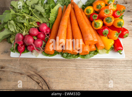 Le carote fresche, lattuga, peperoni e ravanelli su legno stagionato sfondo. Foto Stock