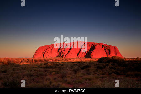 Uluru, o Ayers Rock, è un massiccio monolito di pietra arenaria nel cuore del territorio del nord del centro rosso deserto Foto Stock