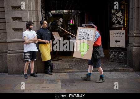 Nel centro cittadino di Barcellona un uomo vestito da Don Chisciotte porta un cartone scudo contro il turismo di massa. Foto Stock