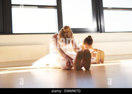 Due giovani ballerine facendo un esercizio, soprattutto per le loro gambe, all'interno dello studio prima che il vero saggio di danza. Foto Stock