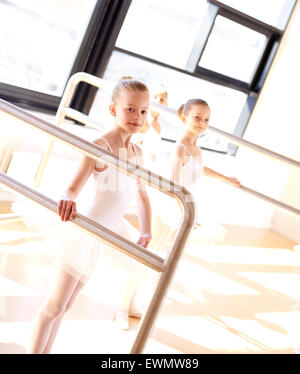 Gruppo di molto i giovani aspiranti ballerine praticare presso il bar in un luminoso ballet studio con una ragazzina guardando Foto Stock