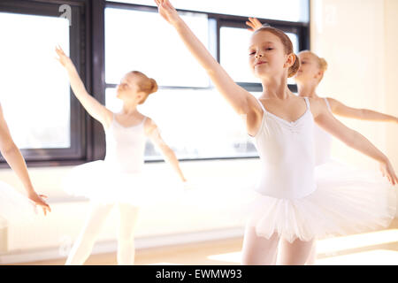 Leggiadre ballerine giovani praticanti un balletto coreografato durante una lezione presso un studio di ballo, vicino fino contro una finestra luminosa Foto Stock