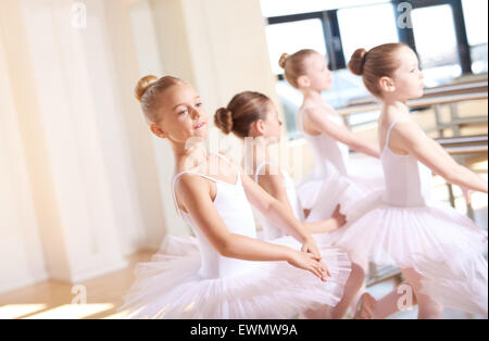 Carino piccolo ballerini indossano Tutus bianco, praticano la loro danza all'interno di Studio durante le loro lezioni di ballo. Foto Stock