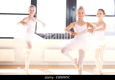 Gruppo di piuttosto leggiadre ballerine giovani praticanti piroette in loro bianca tutus durante un corso di danza in un balletto classico Foto Stock