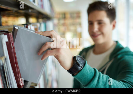 Close up di felice studente Ragazzo con libro in biblioteca Foto Stock