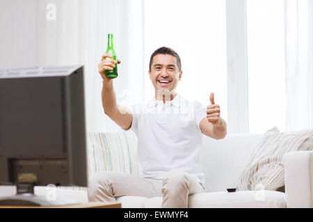 Uomo sorridente di guardare la tv e bere birra in casa Foto Stock