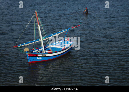 Antica barca a vela in legno e pescatore a Tavira, Algarve, Portogallo Foto Stock