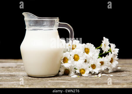 Latte e fiori su un sfondo di legno Foto Stock