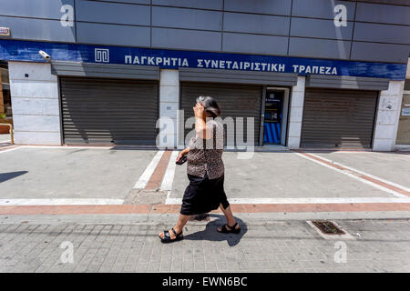 Crete Senior donna che passa accanto a una banca chiusa, Rethymno, Creta grecia anziana anziana anziana anziana anziana donna Grecia economia bancaria Pancretan Co-operativa Banca Foto Stock